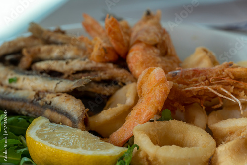 Fried calamari fishes and shrimps on plate in summer restaurant beach in Scalea Italy