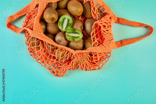 Flat lay Mesh grocery  shopping eco friendly bag with kiwi on blue canvas background, Zero waste cconcept, Local farmers market, shopping mall, top view, copy space, Plastic free items. photo