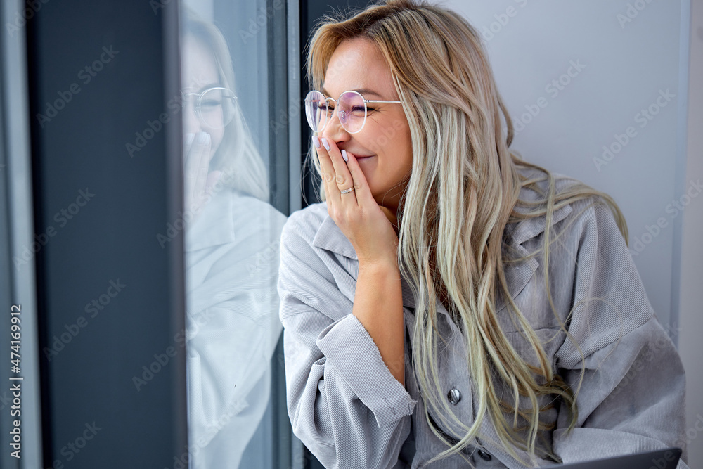 happy female sitting on windowsill at home and looking away, in spectacles, have fun alone, indoors, in domestic atmosphere, dressed in casual clothes. people, human emotions, lifestyle, beauty happy female sitting on windowsill at home and looking away, in spectacles, have fun alone, indoors, in domestic atmosphere, dressed in casual clothes. people, human emotions, lifestyle, beauty