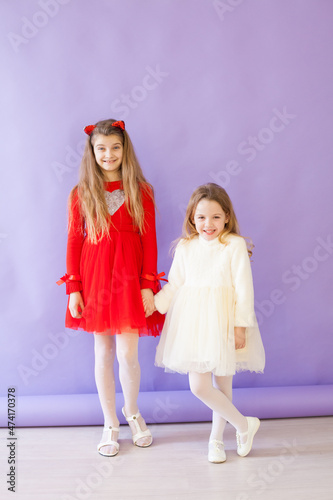two girls in white and red dresses holding hands