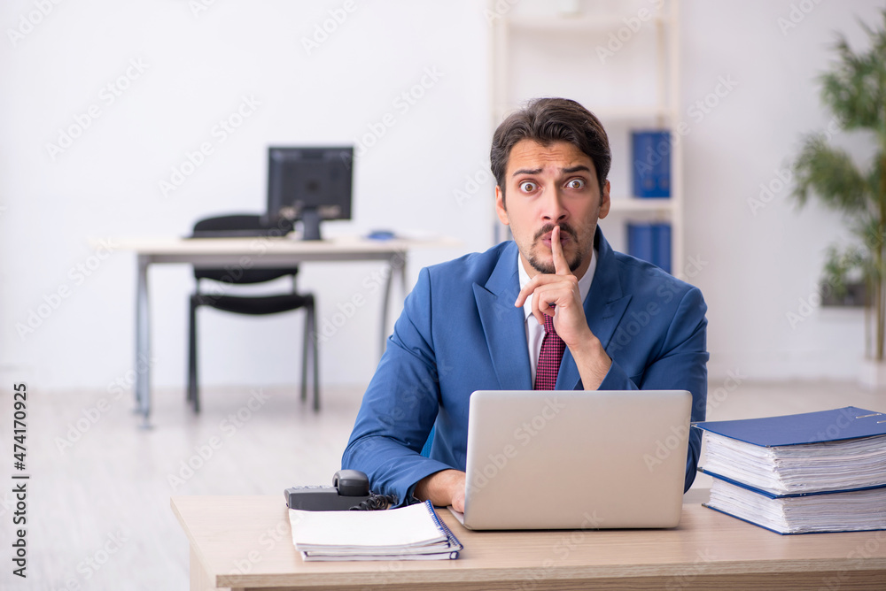 Young male employee unhappy with excessive work in the office Young male employee unhappy with excessive work in the office