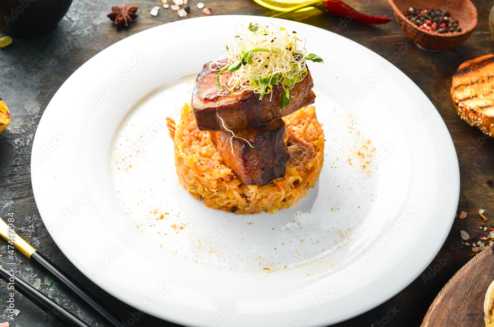 Juicy baked pork ribs with stewed cabbage on a plate. Top view. Juicy baked pork ribs with stewed cabbage on a plate. Top view.