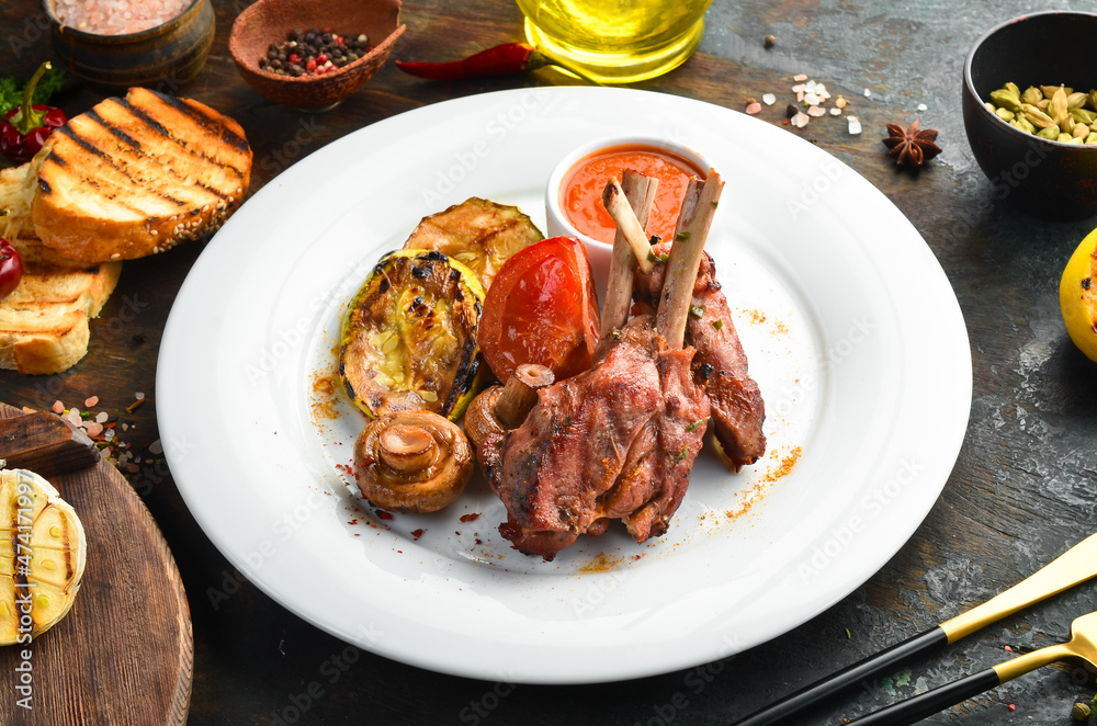 Baked lamb ribs with vegetables on a plate. Top view. Baked lamb ribs with vegetables on a plate. Top view.