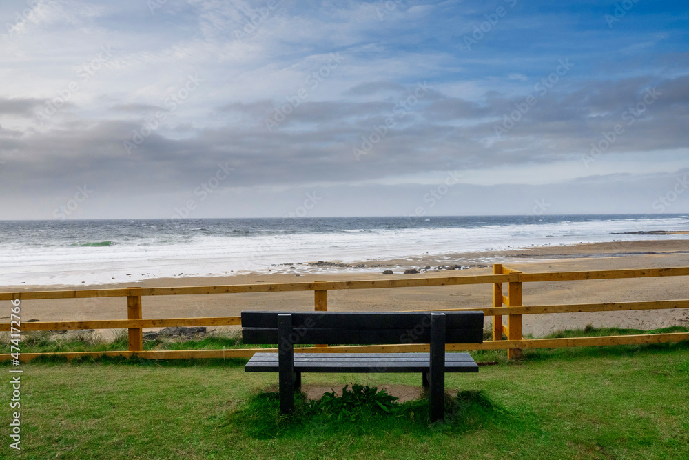 Empty wooden bench with view on amazing Fanore beach, county Clare, Ireland. Beautiful cloudy sky over ocean. Irish landscape. Popular tourist destination.