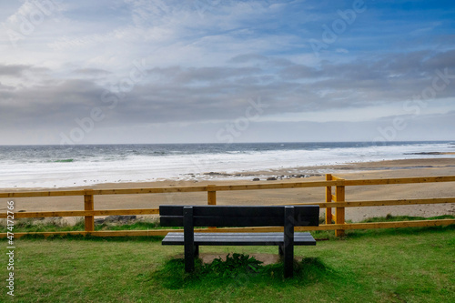 Empty wooden bench with view on amazing Fanore beach, county Clare, Ireland. Beautiful cloudy sky over ocean. Irish landscape. Popular tourist destination. © mark_gusev