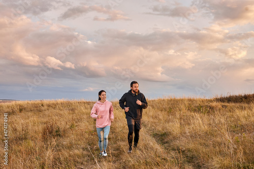 Young couple athlete runners breathing fresh air in morning. Healthy man and woman doing fitness jogging on field. Training run. Free people runs in summer at dawn. fit couple in sports clothes © alfa27