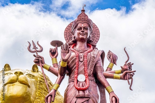 Fotografia A powerful Statue of the Hindu goddess Durga Maa with a golden lion in sacred Ganga Talao