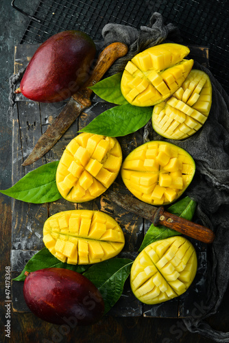 Fresh tasty sweet mango with leaves on old wooden dark background. Rustic style. Top view. Tropical fruits.