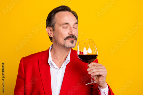 Portrait of handsome good mood peaceful man smell wine enjoying tasty aroma isolated on yellow color background