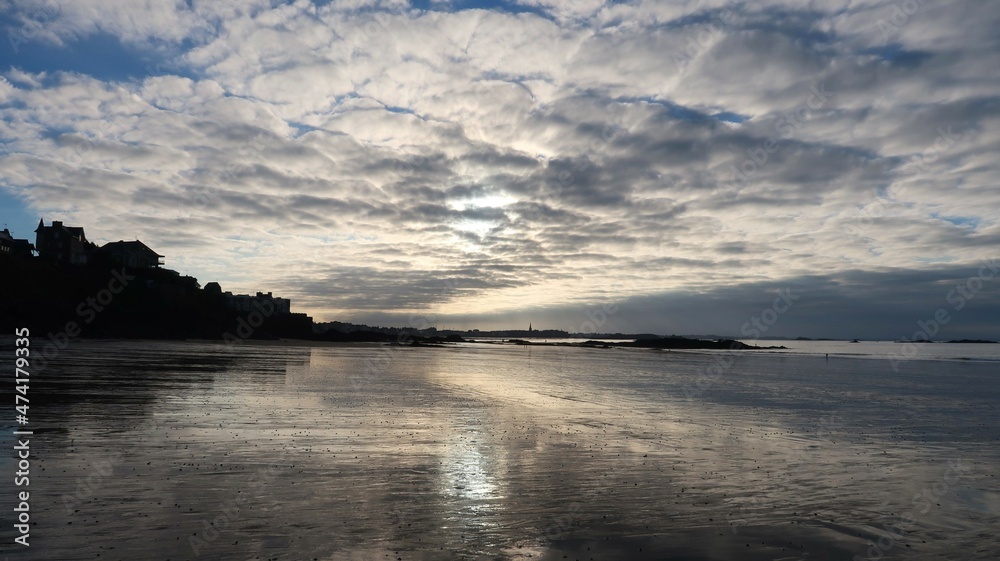Plage du Minihic à Saint-Malo en Bretagne, paysage de côte avec le reflet d'un ciel nuageux sur le sable mouillé, au bord de la mer (France)