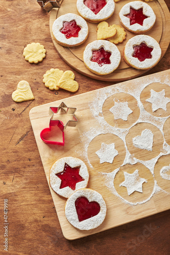 Wooden cutting board with powdered sugar and Linzer cookies, baking decoration process photo