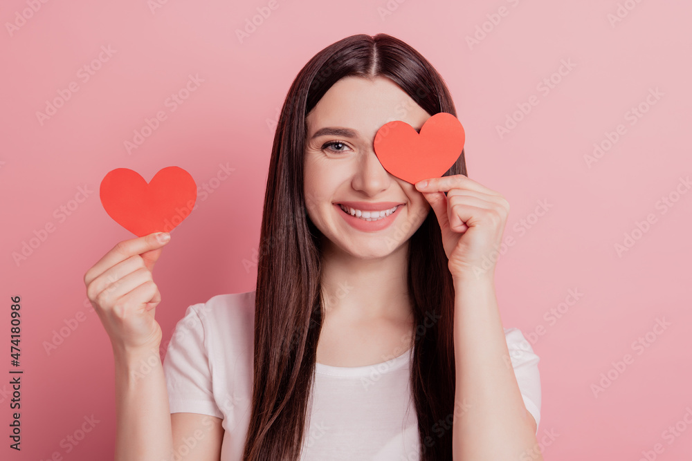 Portrait of attractive lovely cheerful girl happy smile cover eye small little heart isolated over pink background Portrait of attractive lovely cheerful girl happy smile cover eye small little heart isolated over pink background