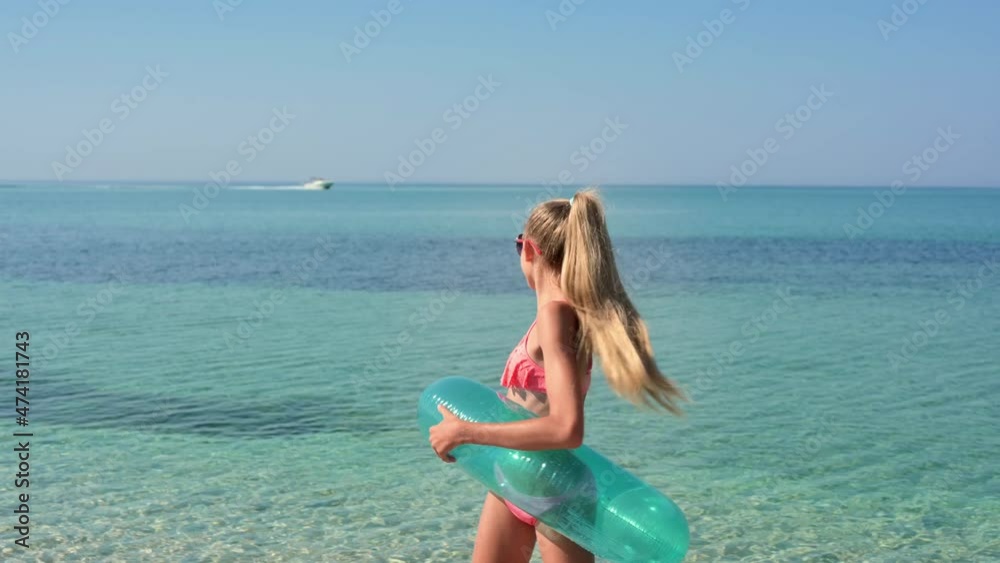 A joyful girl with an unfeeling circle is dancing on the background of the sea. The girl turns and looks at the passing boat A joyful girl with an unfeeling circle is dancing on the background of the sea. The girl turns and looks at the passing boat