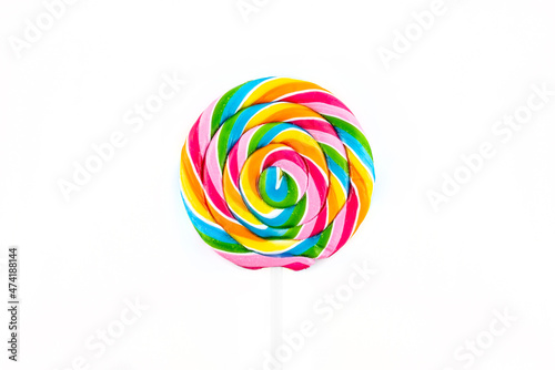 Sweet spiral-shaped colorful lollipop lying in the center, isolated on white background, top view.