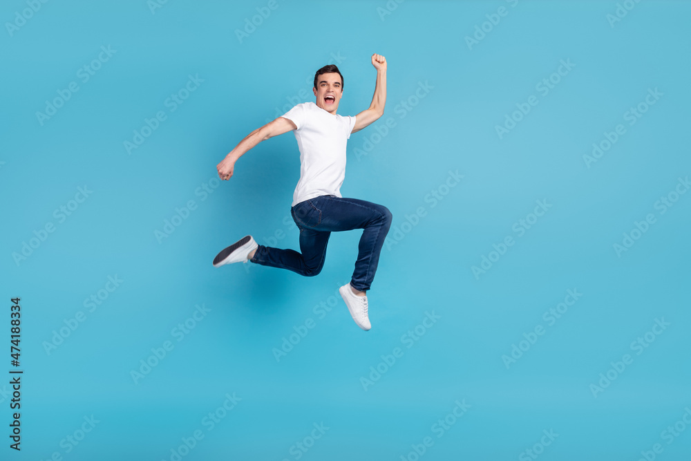 Full size photo of young cheerful guy go run jump up hurry fast isolated over blue color background