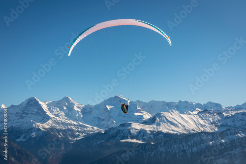 paraglider in the bernese alps.In the background mountain peaks of Eiger, Moench and Jungfrau, Switzerland