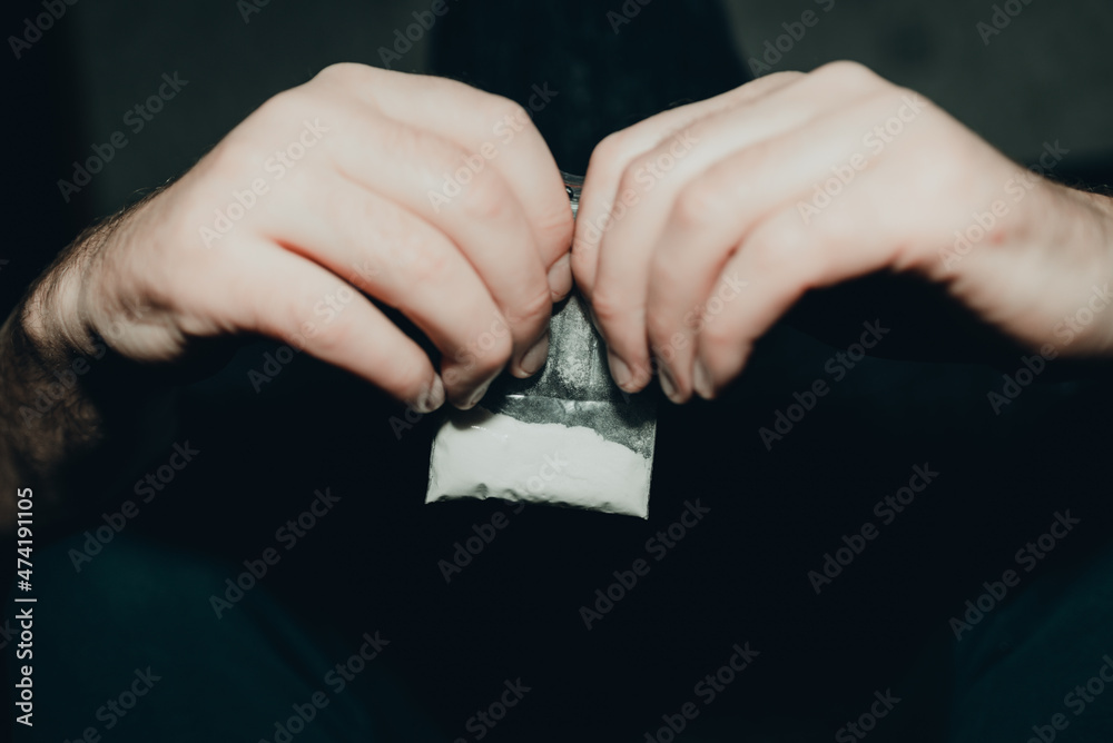 Obraz premium Criminal holding plastic bag with drug.Man holding transparent plastic zip lock bag with drugs. Concept-criminal with drugs.closeup,selective focus,toned.