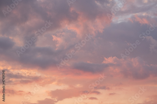 Moody sunset or sunrise sky with rays of light illuminating dark blue and bright and soft pink and orange clouds. no people  clouds only. High contrasts in a stormy sky