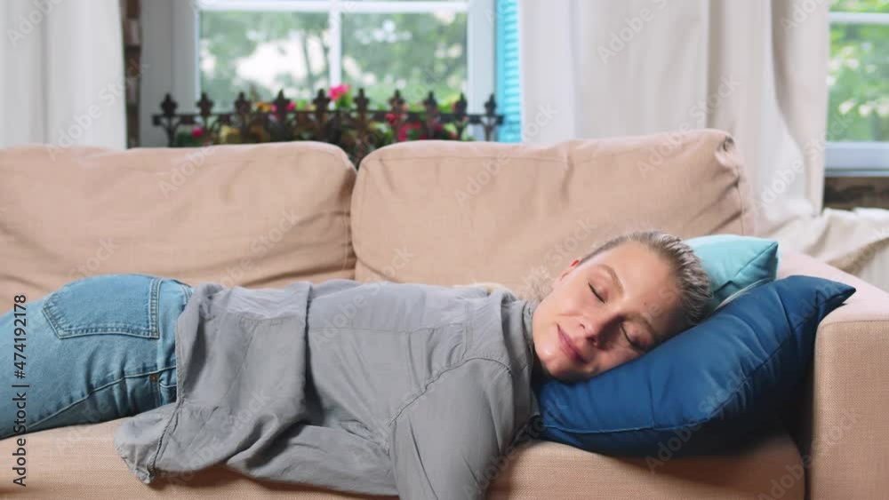 Exhausted young woman sleeping on couch in living room. Realtime Exhausted young woman sleeping on couch in living room. Realtime