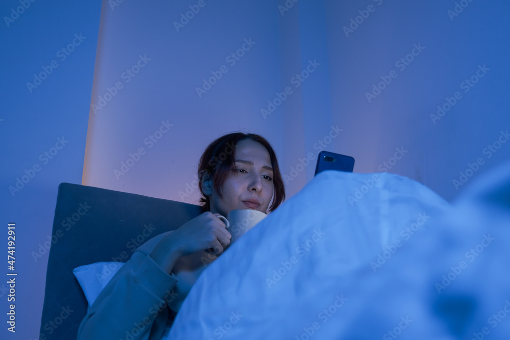 woman spending time on the phone in bed at night and drinking natural herbal tea, woman spending time on the phone at night in bed, woman spending time on the phone in bed at night and drinking natural herbal tea, woman spending time on the phone at night in bed,