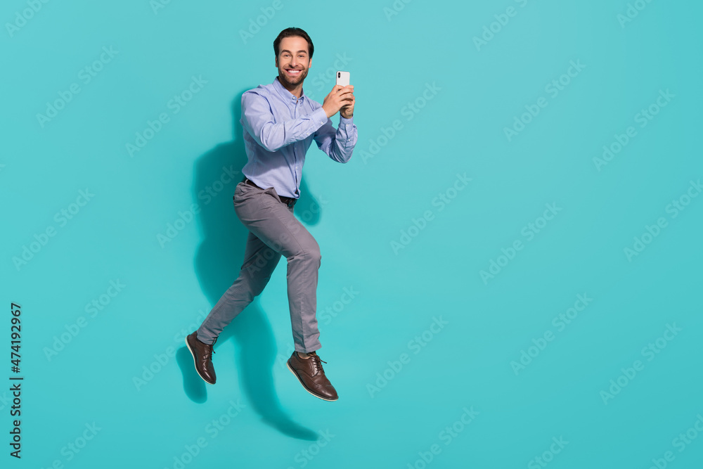 Photo of carefree corporate tourist man jump make travel blog wear violet shirt isolated turquoise color background Photo of carefree corporate tourist man jump make travel blog wear violet shirt isolated turquoise color background