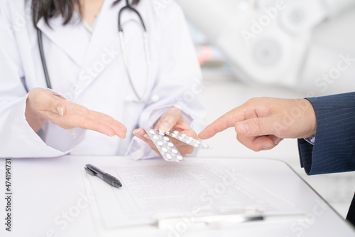 処方薬の説明をする女医と男性患者の手元 photo