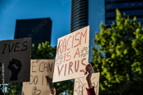 Crowd of people standing with signboards against racism on city street © DavidPrado