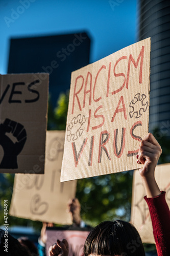 Crowd of people standing with signboards against racism on city street photo