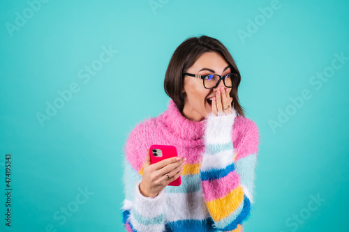 Photos A young woman in a bright multicolored sweater on a blue background with glasses