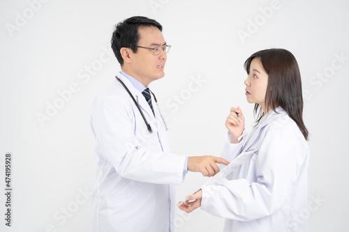 カルテをさして怒る男性医師と驚く女医・白背景 photo