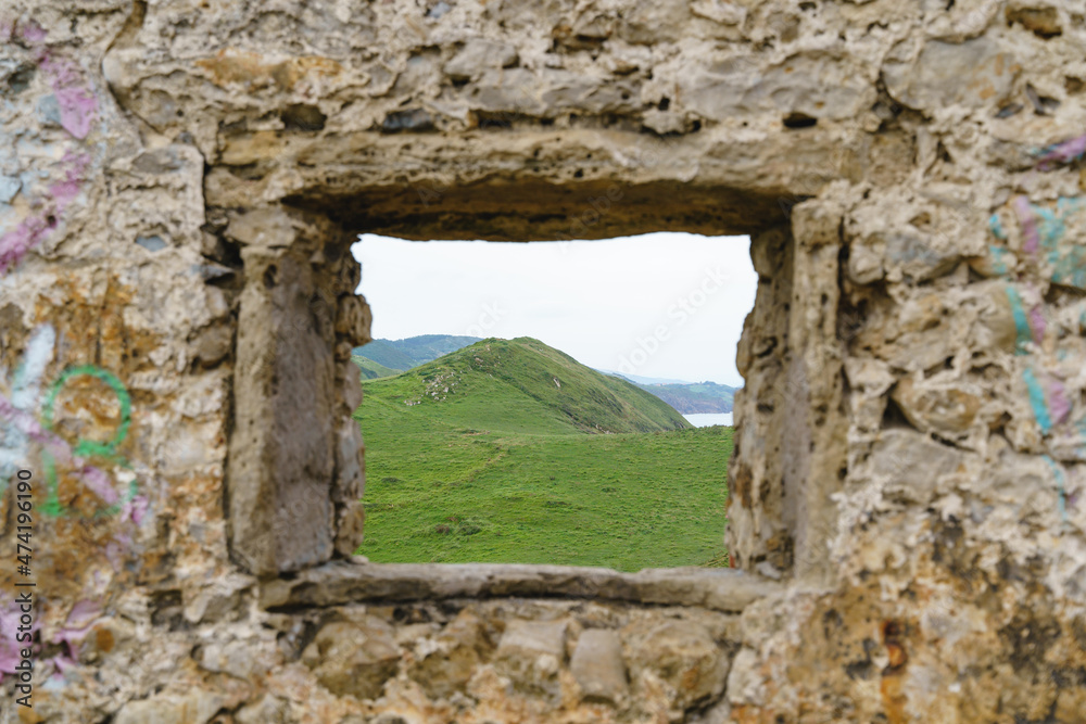 Horizontal front view of mountain landscape in Cantabria. Panoramic view of green mountain framed by a stone window. Nature and travel concept.