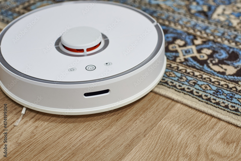White robot vacuum cleaner close-up. Smart House. Automatic cleaning concept. White robot vacuum cleaner close-up. Smart House. Automatic cleaning concept.