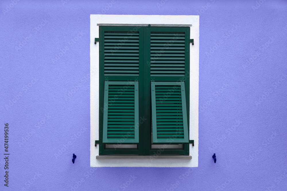 green wooden window with shutters in white frame on blue violet wall