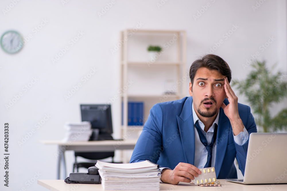Young male employee suffering at workplace Young male employee suffering at workplace