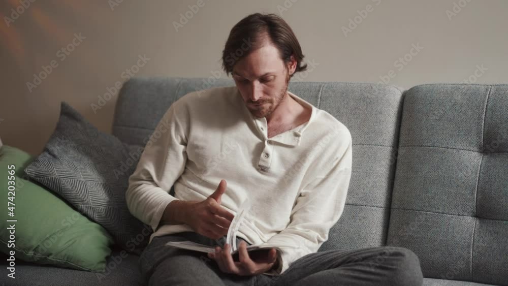 Pensive long-haired man reading book at home Pensive long-haired man reading book at home