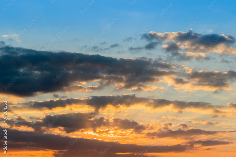 Nature background of evenging sky . Gradation of the blue sky to the four oranges with dark clouds.