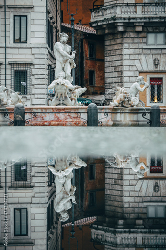 The Fontana del Moro in Piazza Navona reflected on a water puddle photo