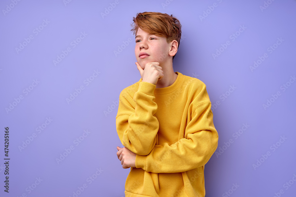 Let me think. Portrait of pensive clever redhead schooler in yellow shirt with puzzled serious expression, child thinking doubting, making choice. indoor studio shot isolated on purple background Let me think. Portrait of pensive clever redhead schooler in yellow shirt with puzzled serious expression, child thinking doubting, making choice. indoor studio shot isolated on purple background