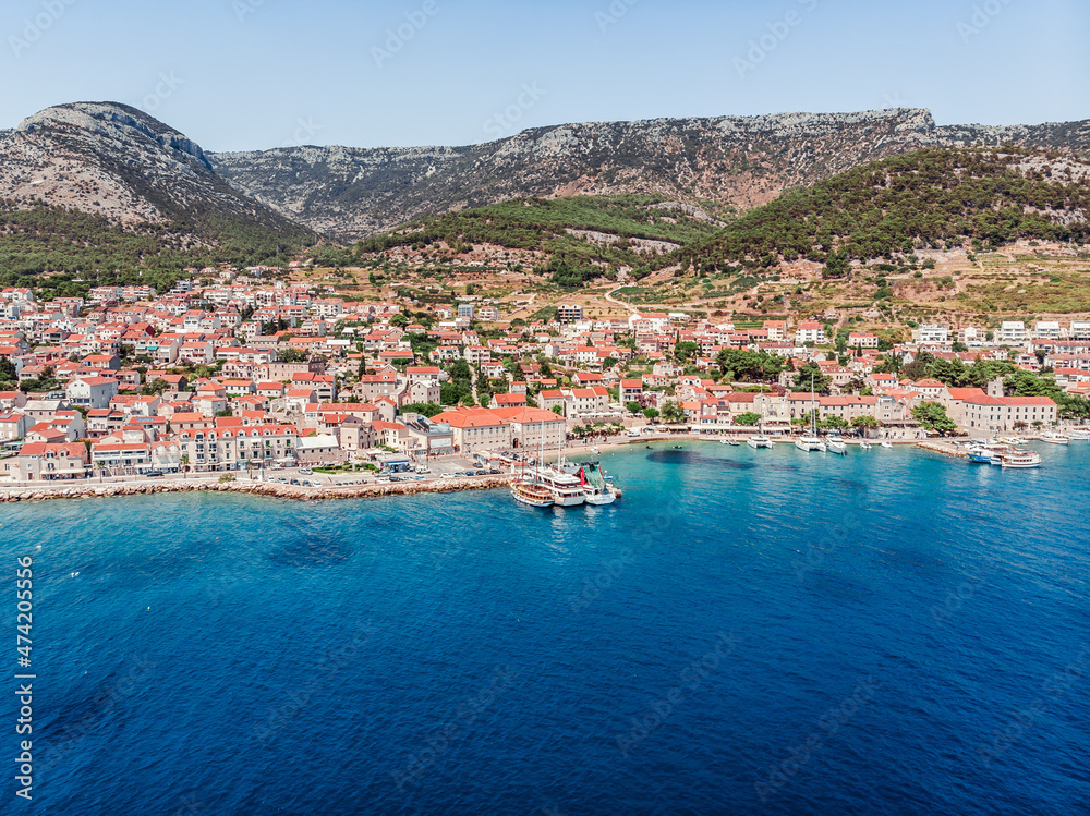 Drone shot of the island of Brac in the Adriatic Sea on the territory of Croatia. The resort center town of Bol view from the drone. Drone shot on the port of the island of Brac. Mountains of Croatia