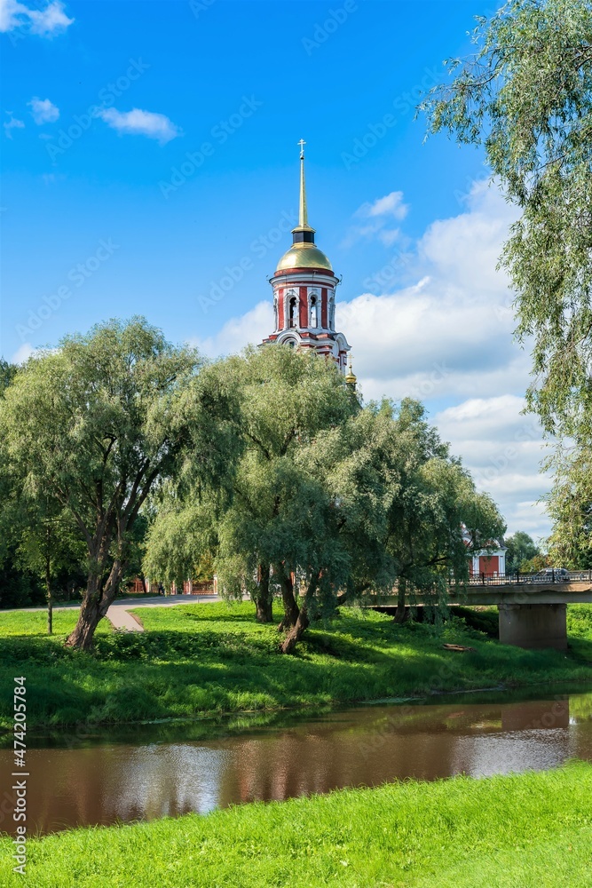 Russia, Staraya Russa, August 2021. The bell tower of the Resurrection Cathedral behind the trees of the park.