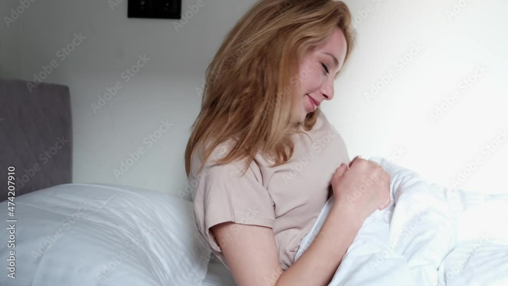 beautiful positive emotional woman getting up in bed stretching and smiling at camera beautiful positive emotional woman getting up in bed stretching and smiling at camera