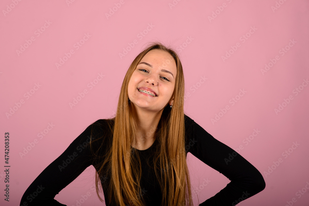 Happiness and facial expressions concept. Woman with smile wears braces on teeth, pink background Happiness and facial expressions concept. Woman with smile wears braces on teeth, pink background