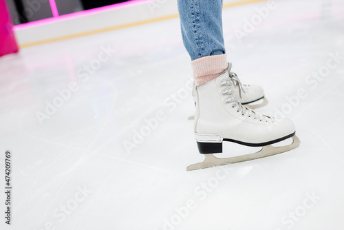 cropped view of woman on white ice skates on frozen rink.