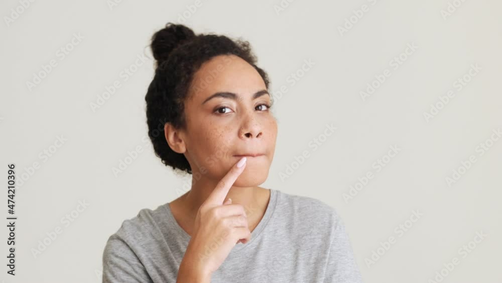 Positive African woman in t-shirt agree with something in the grey studio Positive African woman in t-shirt agree with something in the grey studio