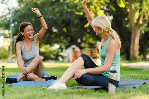 Multiracial women smiling and giving high five during yoga practice