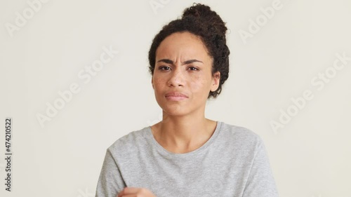 Displeased African woman in t-shirt disagree with something in the grey studio photo