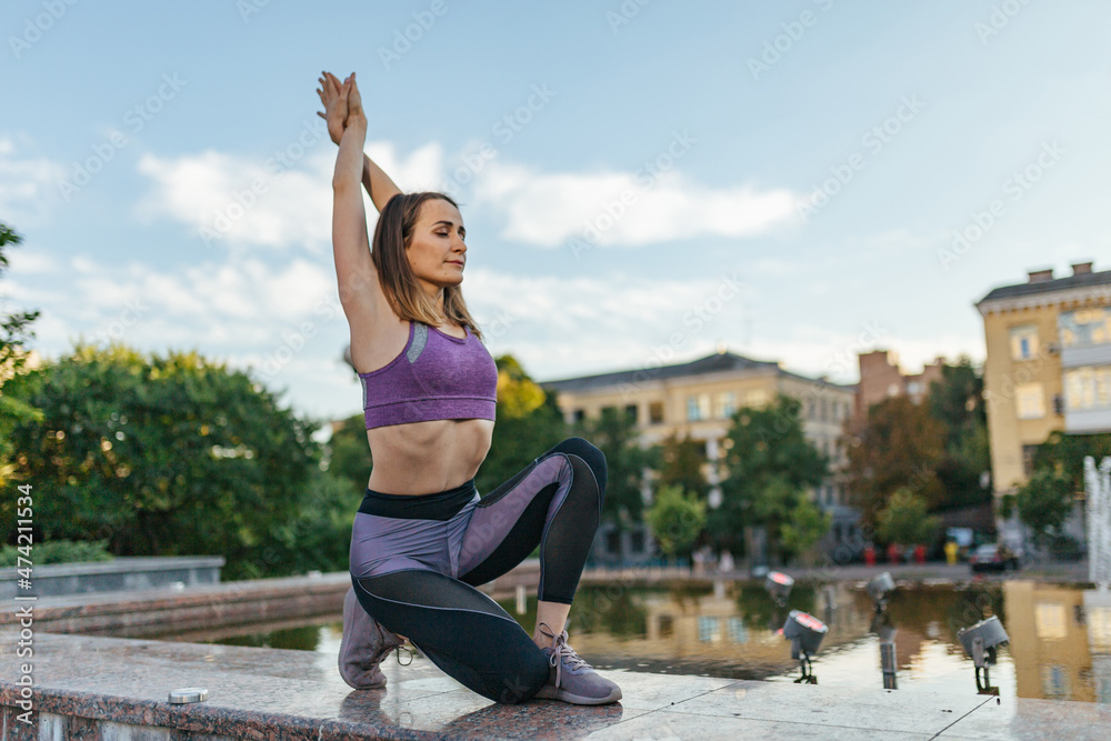 Beautiful girl in sportswear doing yoga poses on the sunset near the fountain in the park , balance, fitness, stretching and relaxation. Beautiful girl in sportswear doing yoga poses on the sunset near the fountain in the park , balance, fitness, stretching and relaxation.