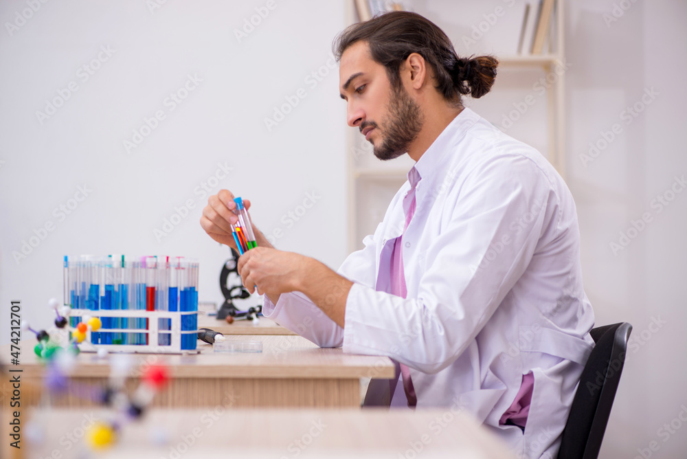 Young male chemist sitting at the desk in the classroom Young male chemist sitting at the desk in the classroom