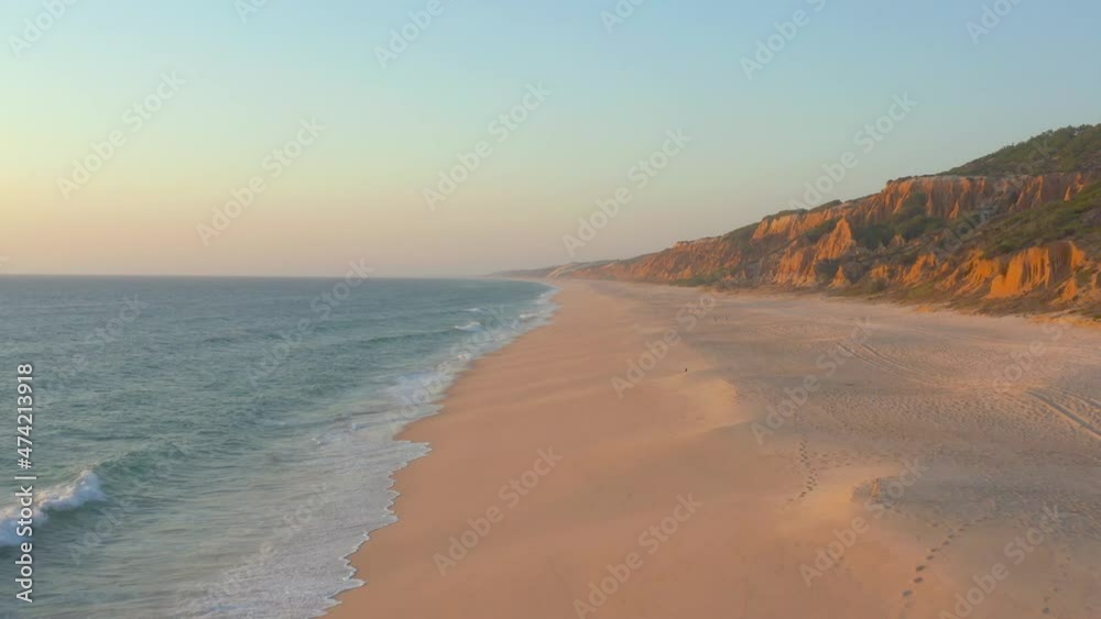 Flying through an empty beach, Arriba Fossil da Praia da Gale Fontainhas seaside cliff rock formation during sunset in the coast shore