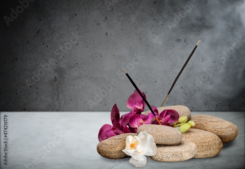 Smoke from burning incense sticks standing on holder with flowers